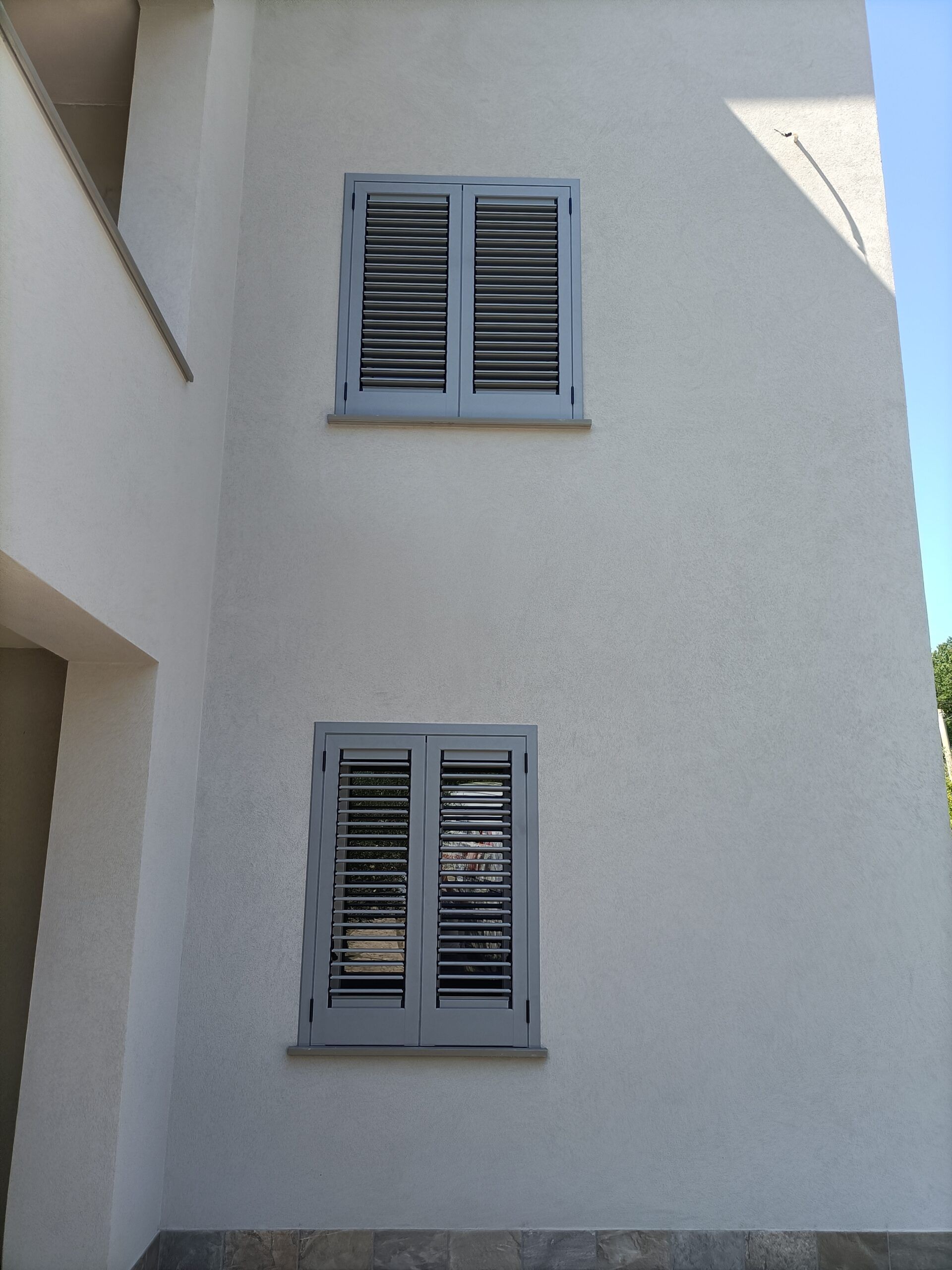 Due persiane grigio chiaro sulla parete bianca dell'edificio