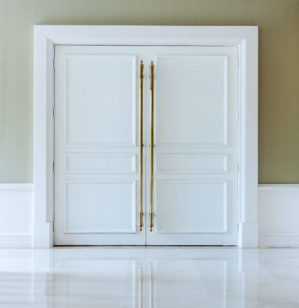 Porta bianca chiusa con maniglie dorate in un hotel di lusso.