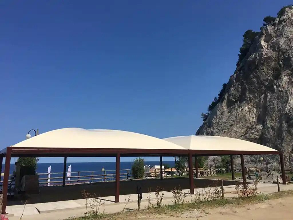 Tende bianche con vista sul mare e montagna.