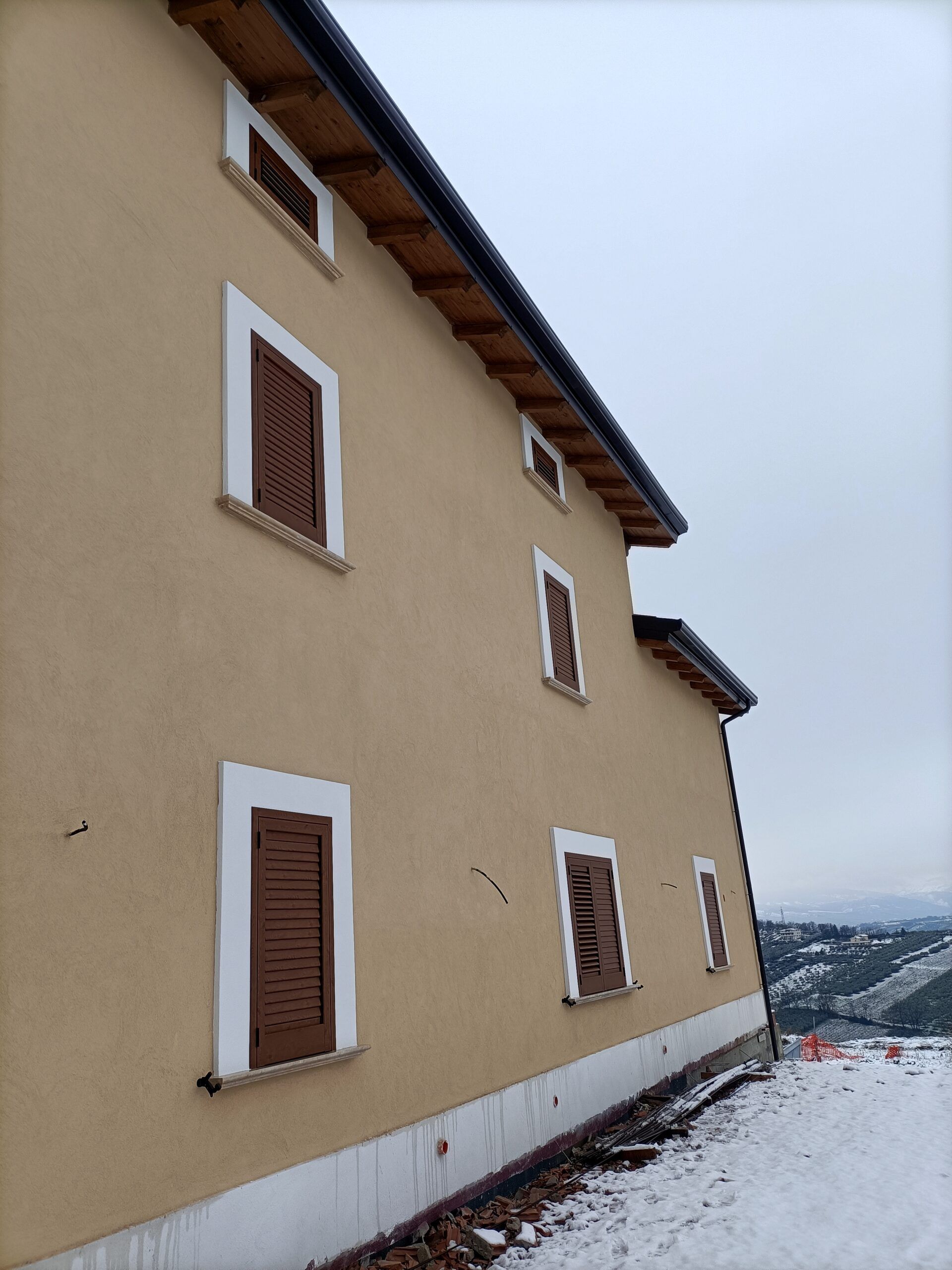 Persiane di legno sul muro di una casa di cui si vede solo la facciata.